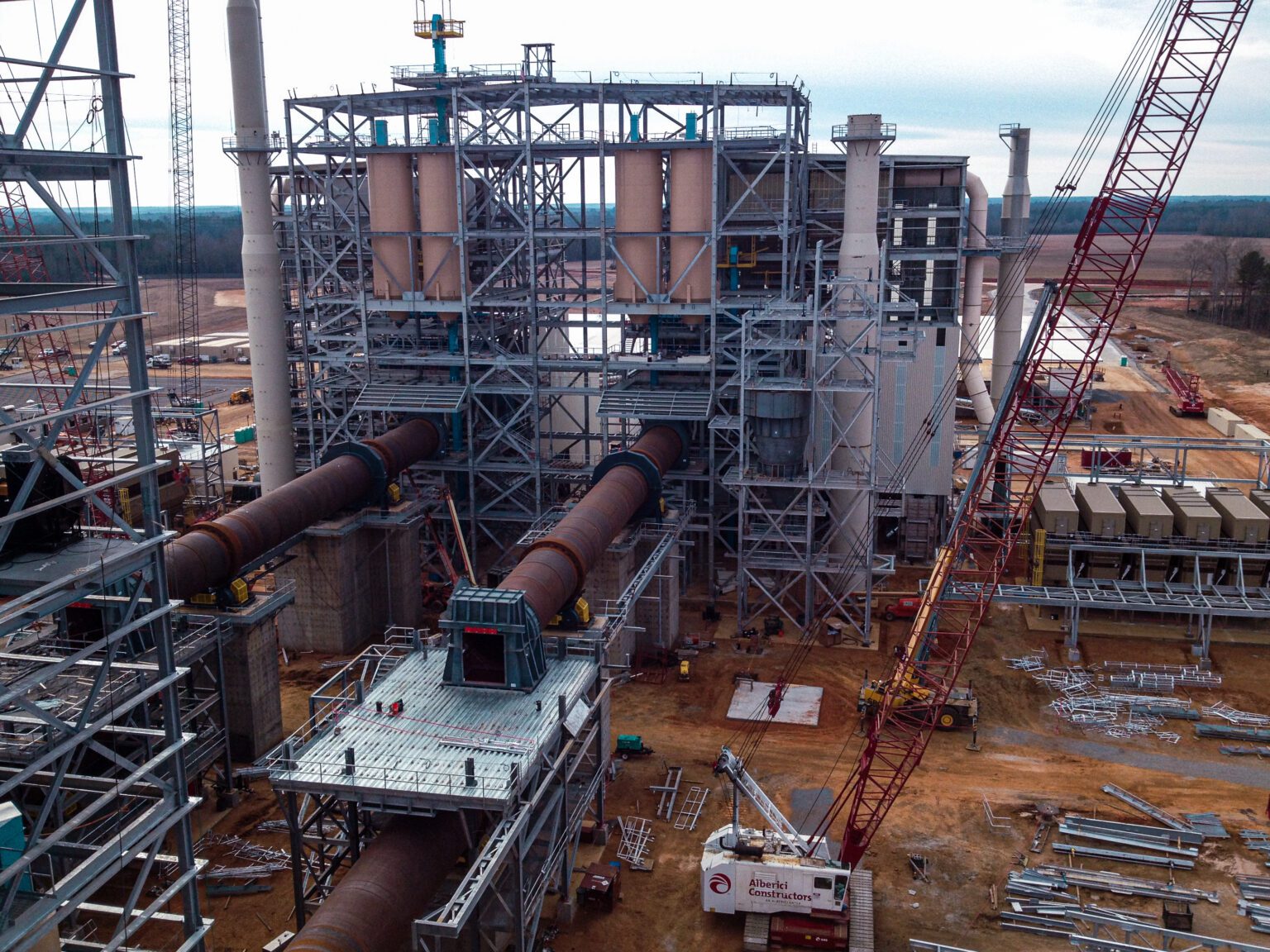 A process facility construction scene showing steelwork, equipment staging, and active site preparation.