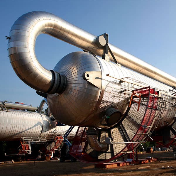 A large-scale refinery expansion project with steel structure, concrete work, and active industrial site operations.