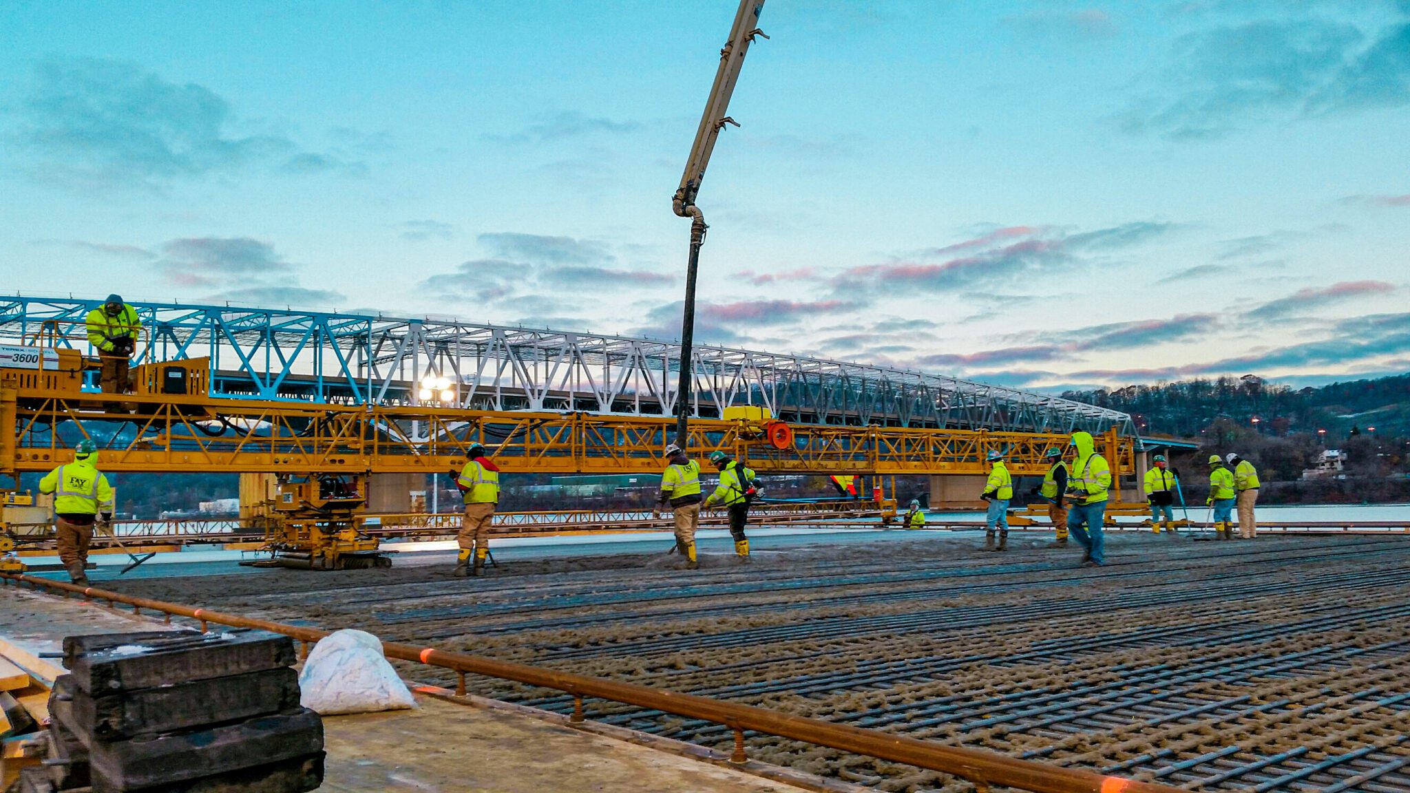 A large commercial crane pad concrete pour underway with heavy equipment, formwork, and active site coordination.